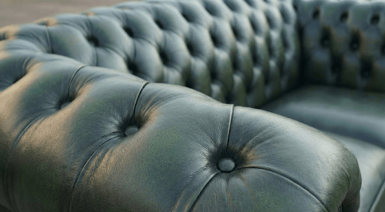 Close-up of dark green leather Chesterfield sofa buttons and tufting