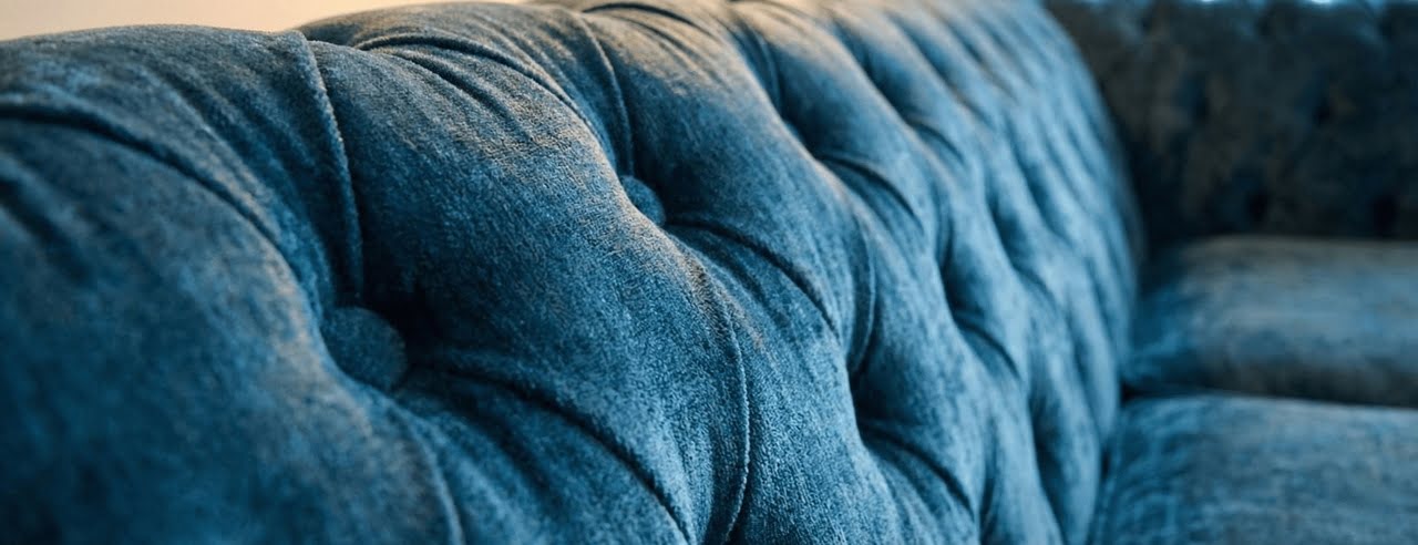 Close-up of deep button-tufting on a blue velvet Chesterfield sofa